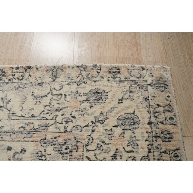 A hand-knotted wool rug, made in India and measuring 4' x 6'. Floral drawing carried across the field inside a traditional...