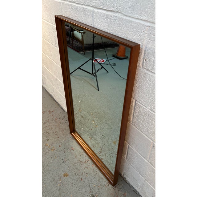 Enhance your space with the timeless appeal of this vintage Mid-Century Modern walnut-framed wall mirror. Featuring a...