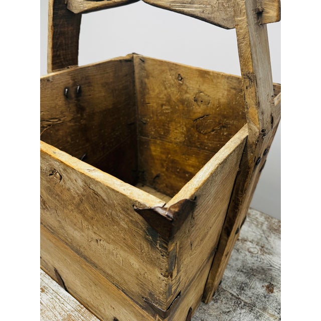 Handcrafted antique Chinese grain bucket in light elm wood with a hand-arched handle and metal joints.