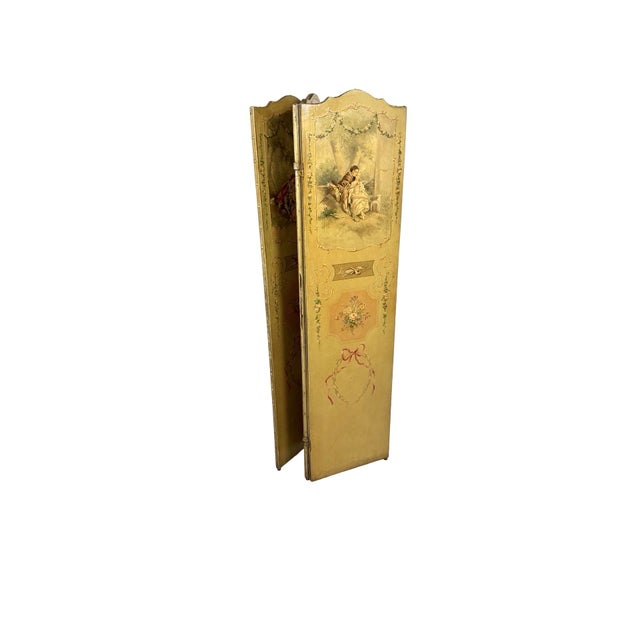 An antique French Louis XV three-panel folding screen, hand-painted on canvas over a wood frame with brass-studded edges,...