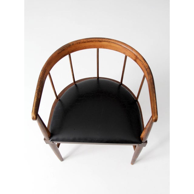 This mid-century spindle back chair features a softly curved continuous rail that wraps gently around the seat, supported...