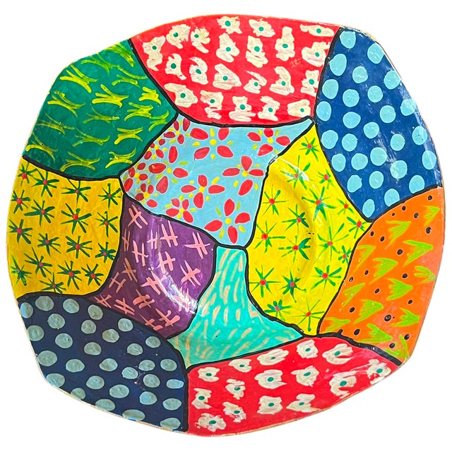 A striking hand-painted paper mache art bowl featuring a bold patchwork of saturated color and graphic pattern. Each...