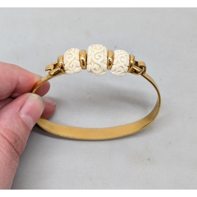 Circa early 1970s goldtone 3 carved faux-ivory pieces cuff bracelet with hinged hook clasp. Marked crown "TRIFARI©" on the...
