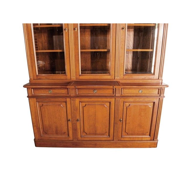 Louis Philippe fruitwood cabinet featuring a sleek glass top. Adorned with window-pane style doors at the top, this...