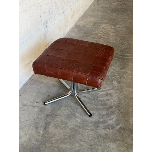 This square ottoman features a striking patchwork top over a minimalist tubular frame. The bold design creates an...
