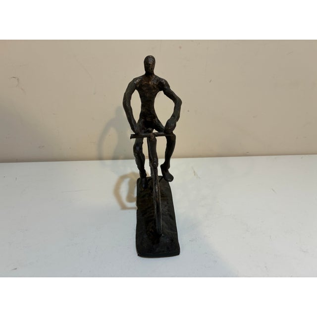 Striking handcrafted metal sculpture depicting a cyclist in motion. The elongated figure, textured surfaces and...