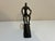 Striking handcrafted metal sculpture depicting a cyclist in motion. The elongated figure, textured surfaces and...