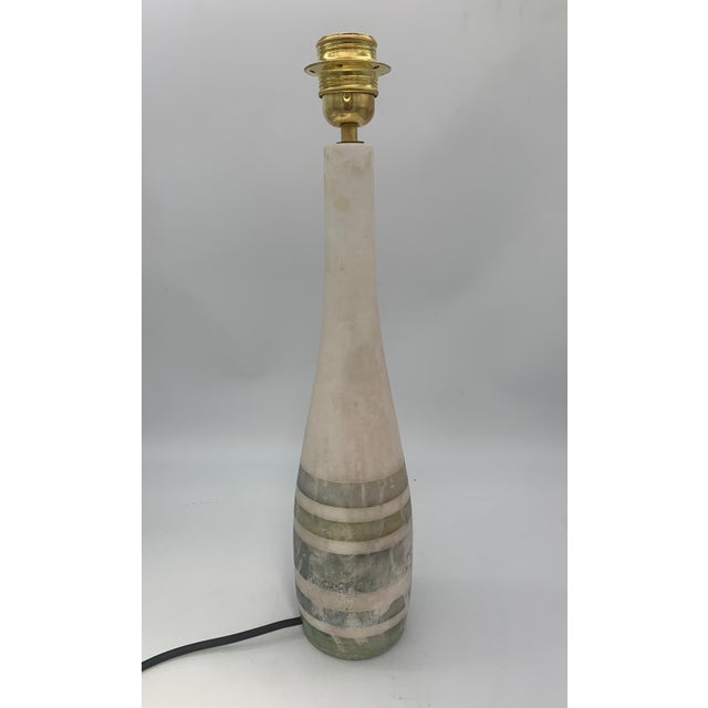 The alabaster lamp features a slender and elegant shape, with a tapered base reminiscent of a contemporary obelisk. The...