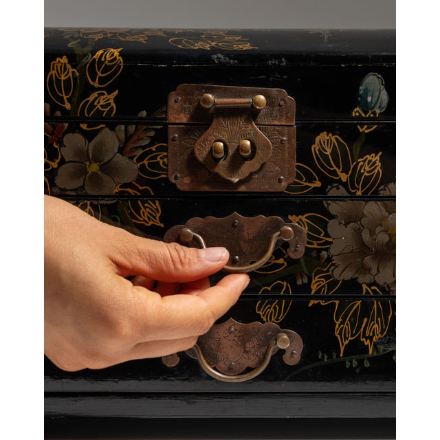 This 20th century Chinese black lacquered box with brass mounts from Asia is finished in black lacquer and painted with...