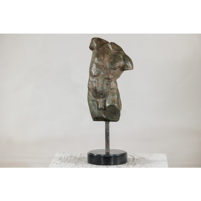 This small bronze male torso is modeled in the classical tradition, presenting a fragmented figure with well-defined...