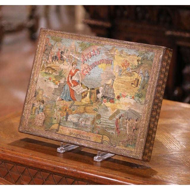 This early 20th century French educational game is presented in its original decorative box, titled Atlas Géographique....