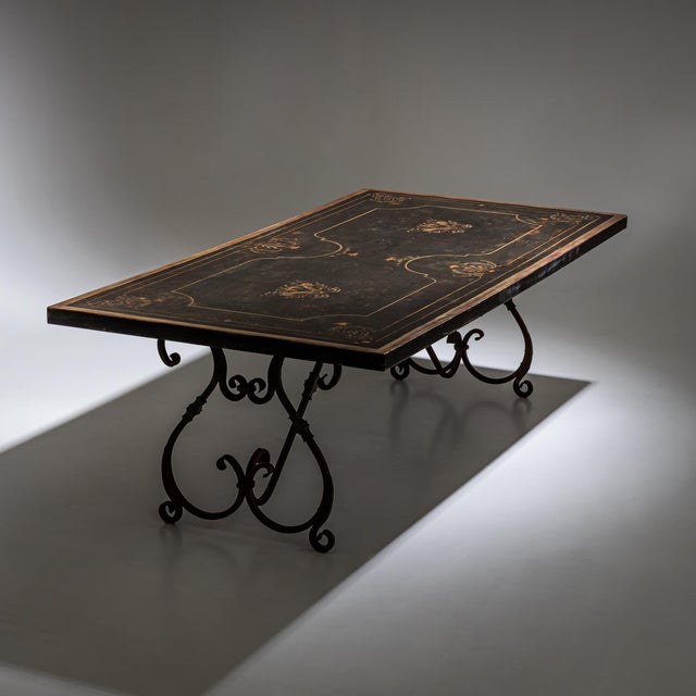 Large rectangular dining table with a long black-painted top featuring hand-painted accents and a patinated Baroque-style...