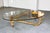 Distinctive tortoiseshell faux bamboo coffee table featuring a sculptural bent frame and oval glass top. Finished in a...
