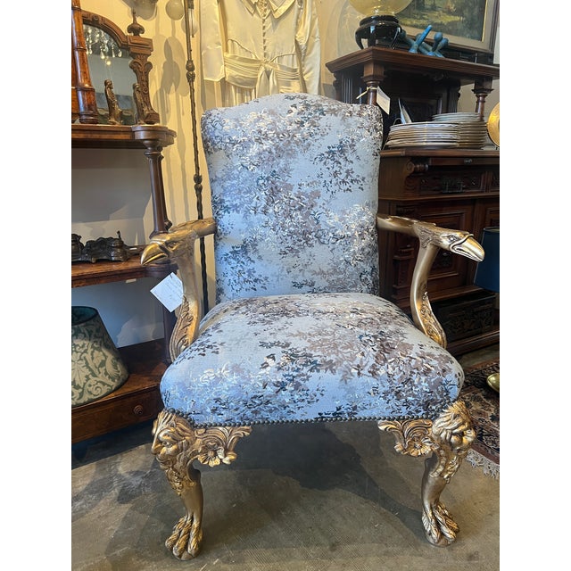 French-style gold gilded armchairs featuring original finish and new upholstery. Intricate carvings of eagles and lions on...