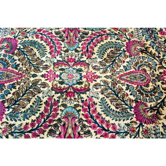 This hand-woven Persian Kirman rug from the 1930s features an intricate all-over floral design on a cream field. The...