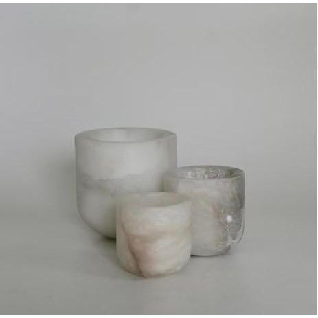 The Luce Tealight Holder by Michael Verheyden highlights the soft, translucent beauty of alabaster, casting a warm,...