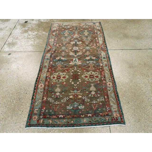 This Mid-20th century Persian Malayer rug, measuring 3' 1" x 6' 2", showcases the village weaving tradition of the Malayer...