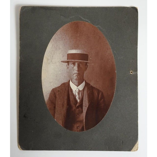 Early 20th century sepia tone albumen portrait photograph of stoic man in straw boater hat. Unsigned. Unframed, oval photo...