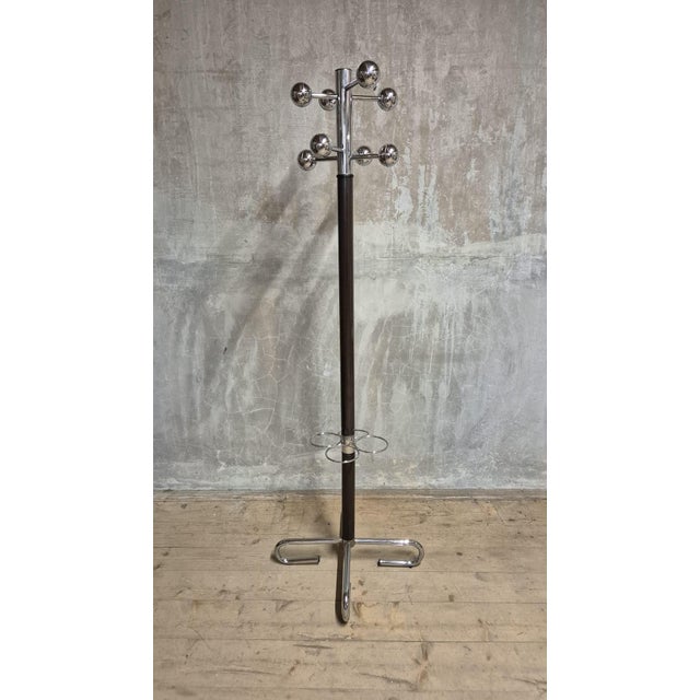 A distinctive vintage freestanding coat rack combining a dark wooden central column with polished chrome-plated metal...