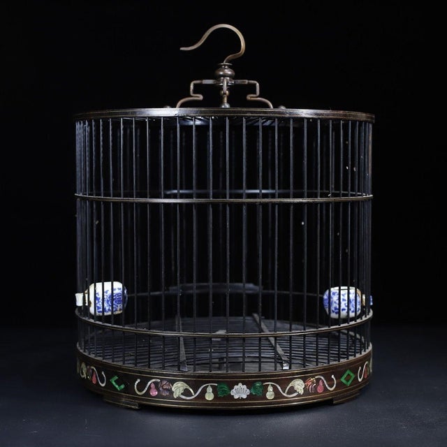 This is an intricately crafted cylindrical wooden birdcage, featuring a striking array of decorative elements. The cage is...
