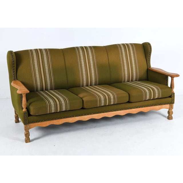 A mid century modern Danish upholstered sofa with carved oak legs/base and arms. Very 1960's and similar to designs by...