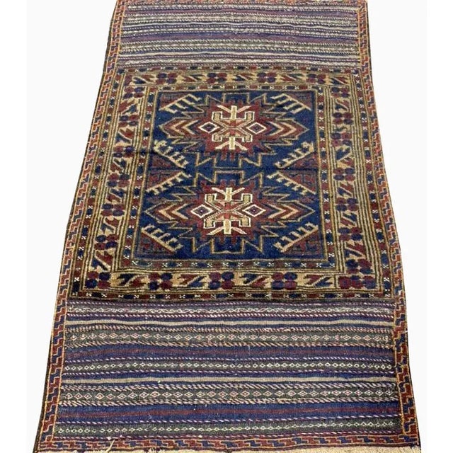 Handwoven Ghochan rug featuring an abstract medallion design on a multi-colored field and ivory border accented in shades...
