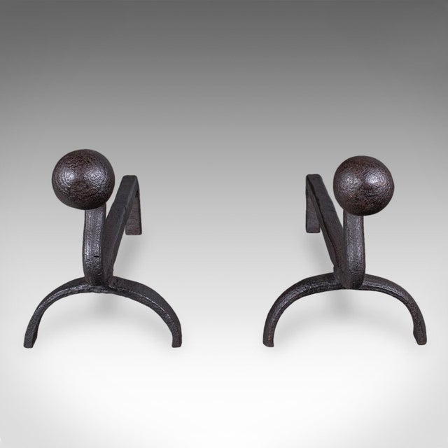 This is a pair of antique andirons. An English, blacksmith made wrought iron fire dog, dating to the late Victorian...