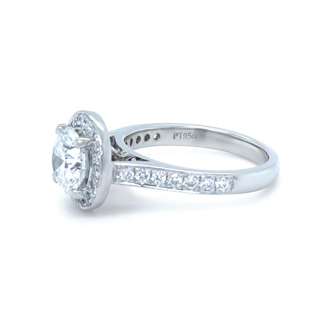 A timeless platinum engagement ring featuring a round brilliant cut diamond in a classic four-claw setting, surrounded by...