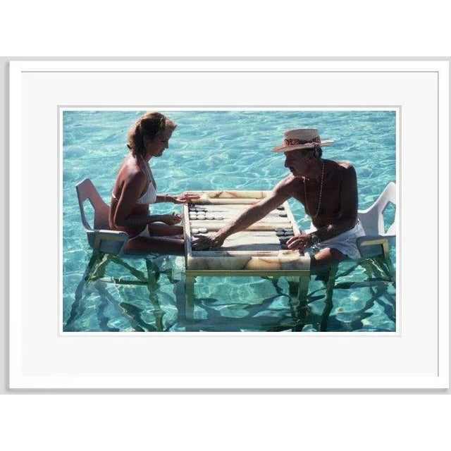 Keep your cool' by slim aarons open edition framed in white wood frame carmen alvarez enjoying a game of backgammon with...