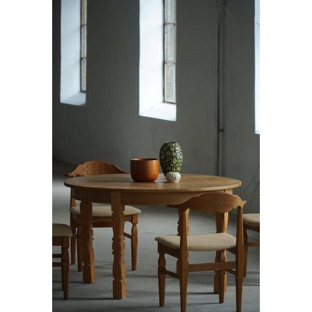 A beautiful and sculptural round oak dining table made in the style of Henning (Henry) Kjærnulf in Denmark during the...