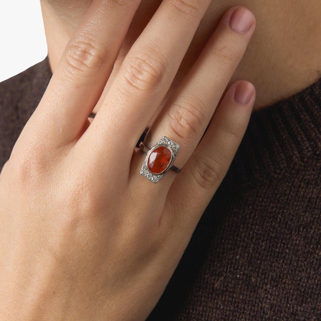 This captivating Art Deco dinner ring showcases a vibrant oval fire opal, glowing with flashes of warm orange and red that...