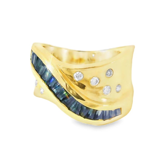 Elegant 14K yellow gold wide band featuring 17 baguette-cut sapphires and 7 round diamonds, a timeless designer ring....