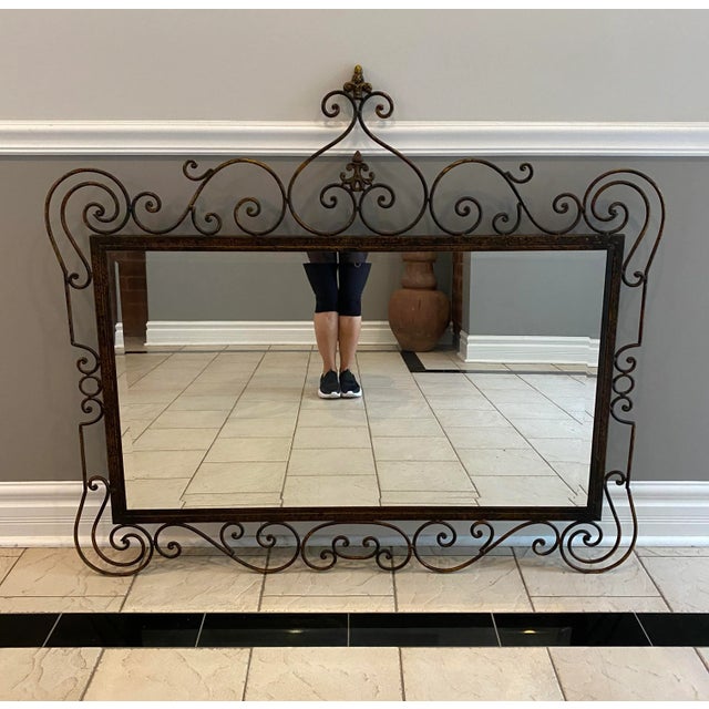 Rare vintage French large scale wrought iron mirror with a beveled edge design. Featuring an exquisite scrolling whimsical...