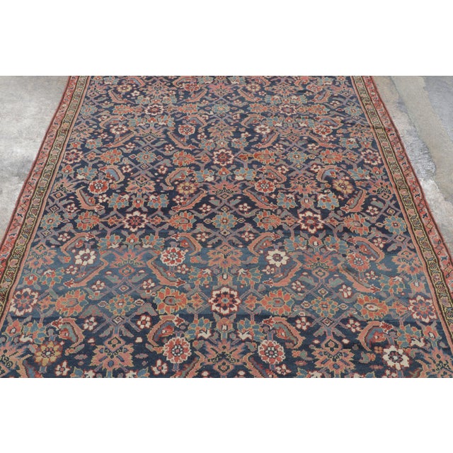 This antique 5x8 Persian rug is a richly detailed early 20th-century weaving distinguished by its deep navy field and...