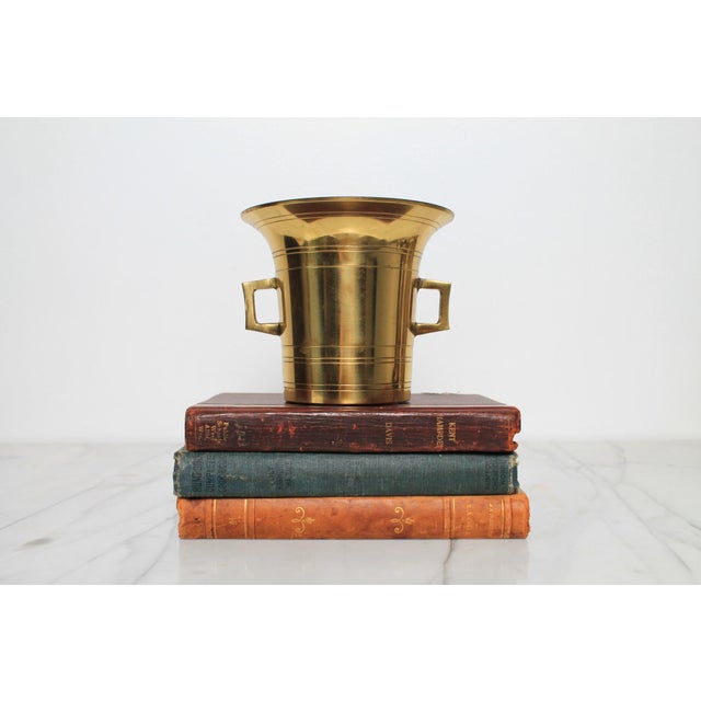 Vintage heavy cast-brass apothecary mortar featuring a flared rim and dual side handles, traditionally used for grinding...