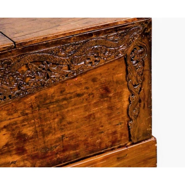 Hand-carved wooden storage chest with intricate dragon and floral motifs across the front panel. This piece is constructed...