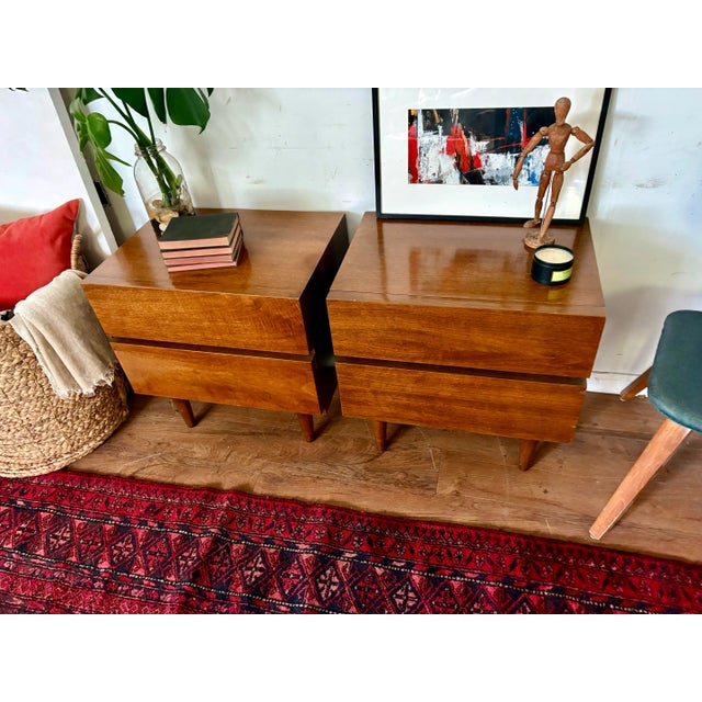 A pair of vintage MCM walnut clad nightstands by American of Martinsville. Clean minimalist style on these 2 drawer...
