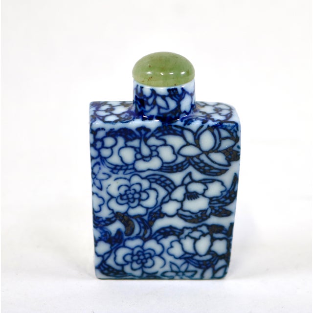 The vintage blue and white floral Chinese snuff bottle with a green stone top is a handmade collectible from China....