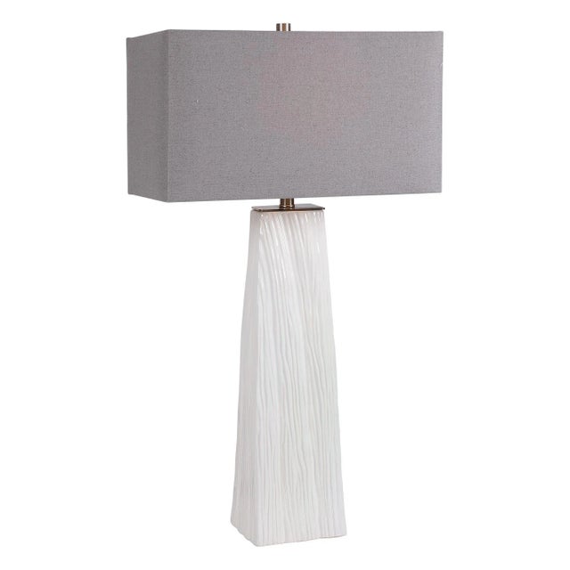 Elegant And Versatile, This Table Lamp Features A Gloss White Ceramic Base Featuring Organic Hand Carved Details And...