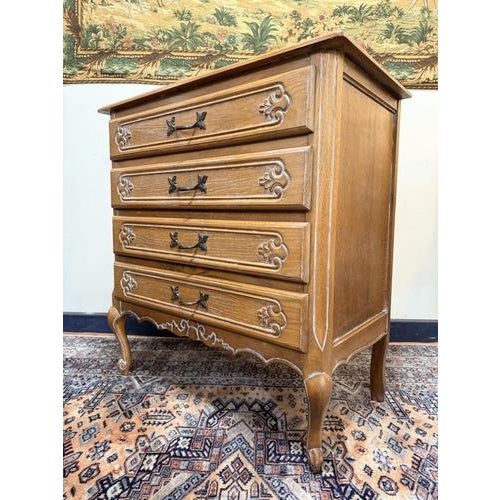 A charming French provincial chest of drawers dating to the mid-20th century, crafted from pine with a soft white waxed...