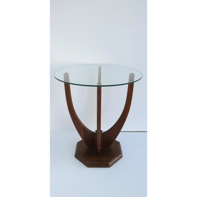 An elegant sculptural walnut wood and glass side or end table, Midcentury Modern design period, circa mid-20th century....
