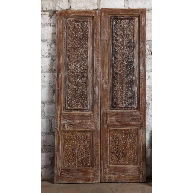 Elevate your interiors with this magnificent antique carved double door, richly detailed with hand-hammered brass studs...