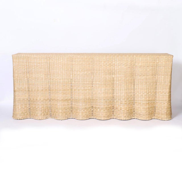 A long wicker drapery ghost console crafted with woven reed over a sturdy metal frame with the highest quality.