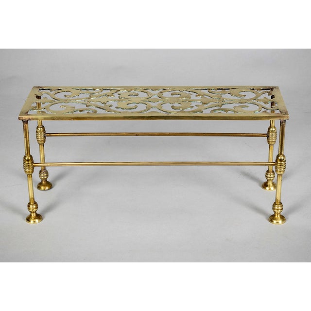 Vintage rectangular brass trivet with reticulated top decorated with C-scrolls and arrows raised on elegant slender legs...