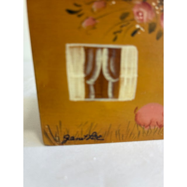 A whimsical hand-painted house-shaped box by folk artist Janet Lee, with a gabled roof decorated in roses and hearts and...