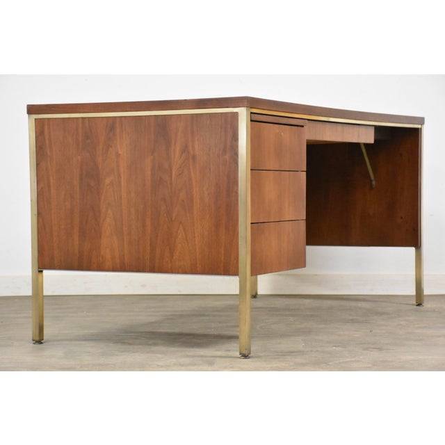 A mid century modern walnut desk made by Alma Furniture with light brass accents. Finished back. Professionally...