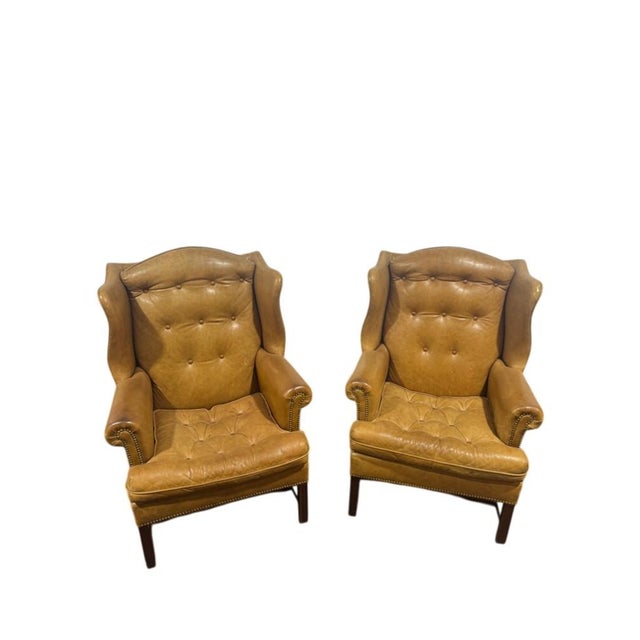 An old school favorite pair of Hancock and Moore tufted leather wingback chairs with a stretcher base. They combine a...