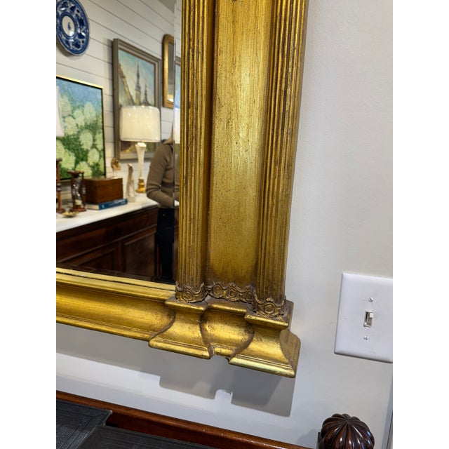 Neoclassical or Federal style mirror with classical architectural elements like columns. Framed in a gilded, gold toned...