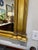 Neoclassical or Federal style mirror with classical architectural elements like columns. Framed in a gilded, gold toned...