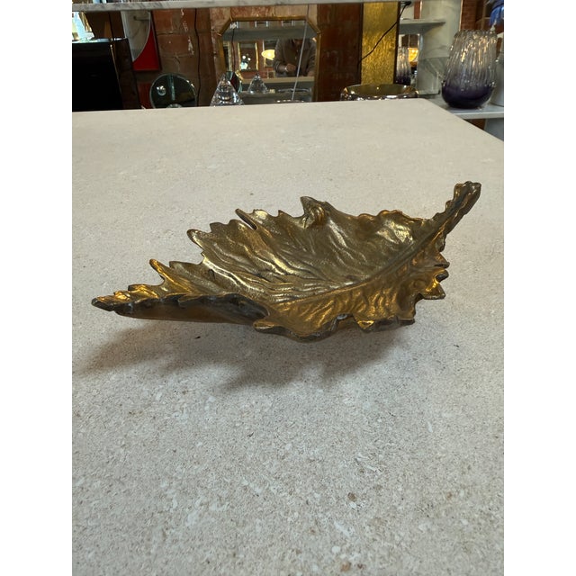 Beautiful vintage brass dish crafted in the shape of a maple leaf, featuring detailed veining and a naturalistic,...